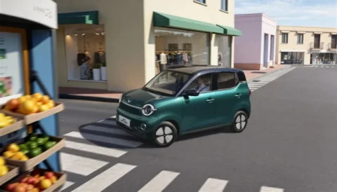 Green fifth-generation Wuling Hongguang MINIEV driving through a city street
